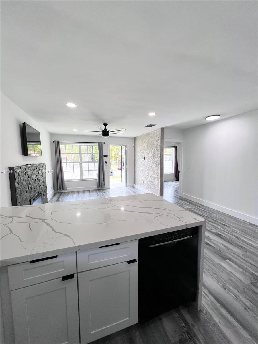 A kitchen island with a white marble countertop overlooks a living area with gray flooring — 2425 SW 26th Ln, Miami FL 33133, MIAMI, FL
