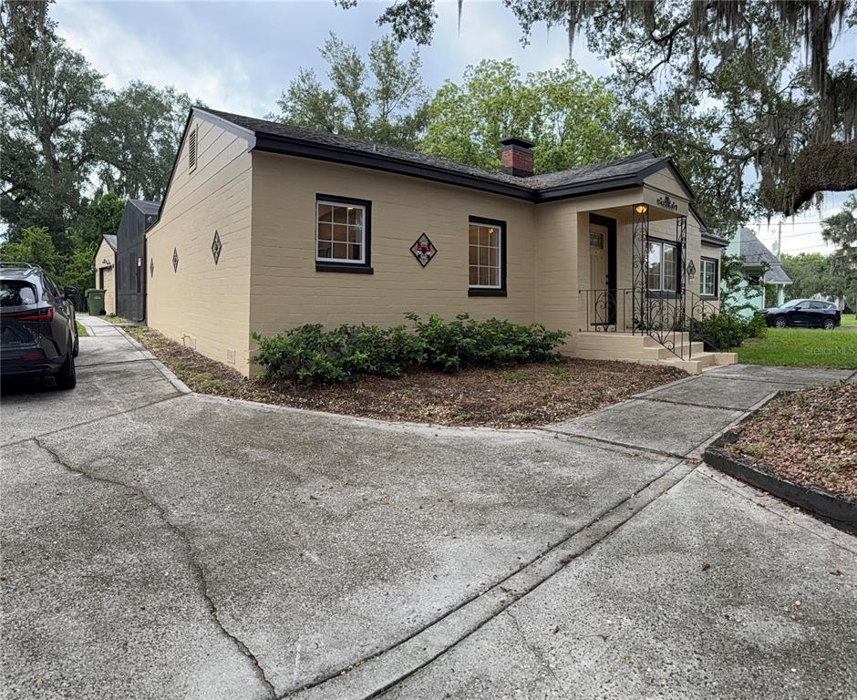 A tan, single-story house with a dark roof and black trim sits on a grassy lot — 1200 SUNSHINE AVENUE, LEESBURG, FL