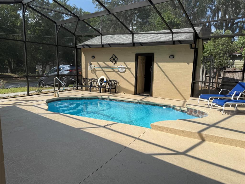 A screened-in patio features a small swimming pool with a waterfall and two lounge chairs — 1200 SUNSHINE AVENUE, LEESBURG, FL