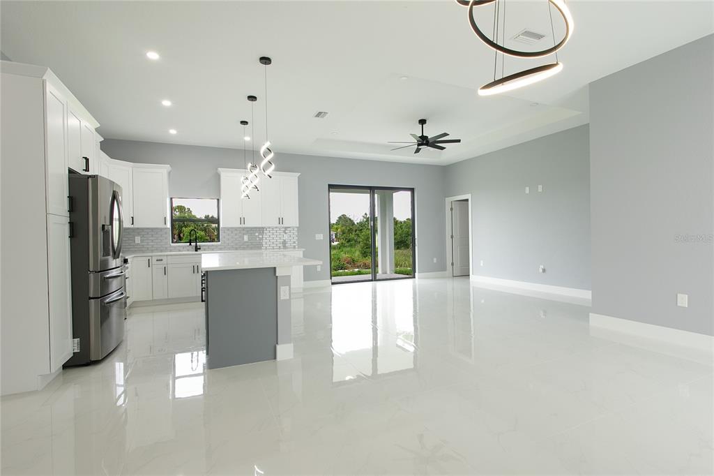 A modern open-concept kitchen and living area with white cabinets, gray walls, and tile floors — 3508 29TH STREET SW, LEHIGH ACRES, FL