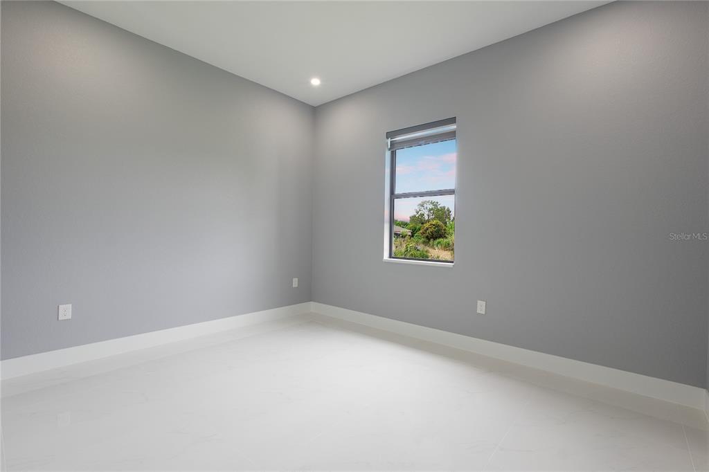 An empty room with gray walls, white tile flooring, and a single window — 3508 29TH STREET SW, LEHIGH ACRES, FL