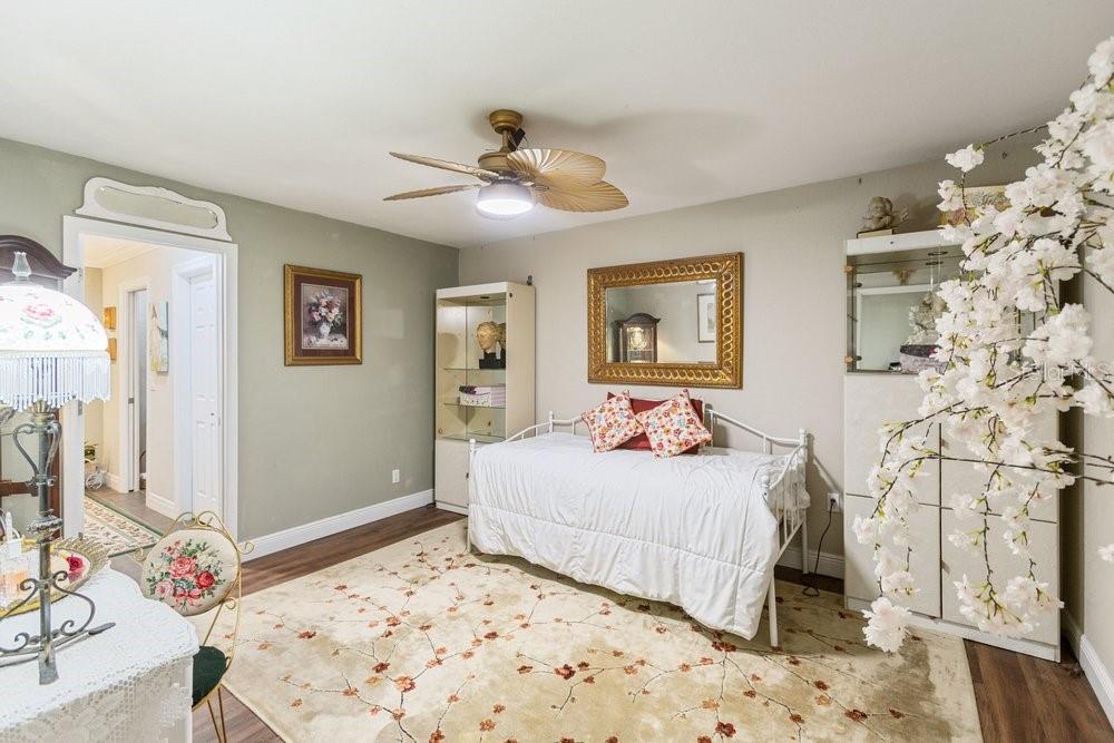 A bedroom features a daybed, a floral area rug, a ceiling fan, and decorative shelving — 13502 WHITBY ROAD, HUDSON, FL