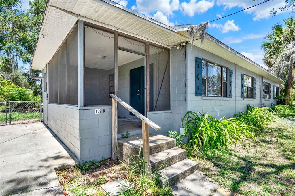 A gray concrete block house features a screened-in front porch and a concrete walkway — 1220 MORIN STREET UNIT B, EUSTIS, FL