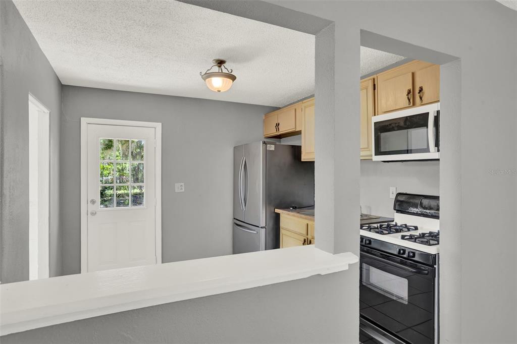 A kitchen features light wood cabinets, stainless steel appliances, and a white pass-through counter — 1220 MORIN STREET UNIT B, EUSTIS, FL