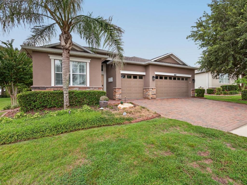 A single-story house with a brick driveway, two garage doors, and a palm tree — 3831 SANIBEL STREET, CLERMONT, FL
