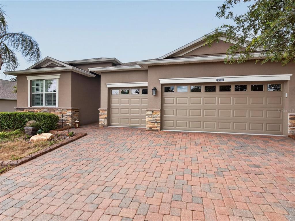 A single-story house with a paved driveway, two garage doors, and stone accents on the exterior — 3831 SANIBEL STREET, CLERMONT, FL