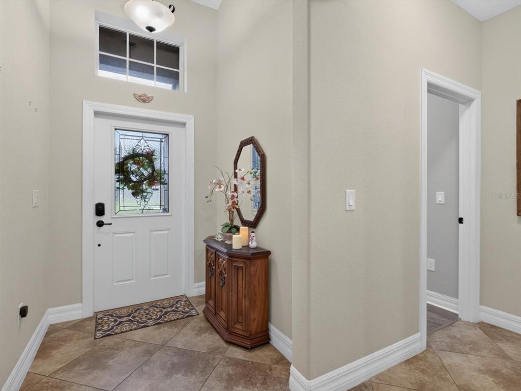 An entryway features tile flooring, a white front door with glass, and a wooden console table — 3831 SANIBEL STREET, CLERMONT, FL