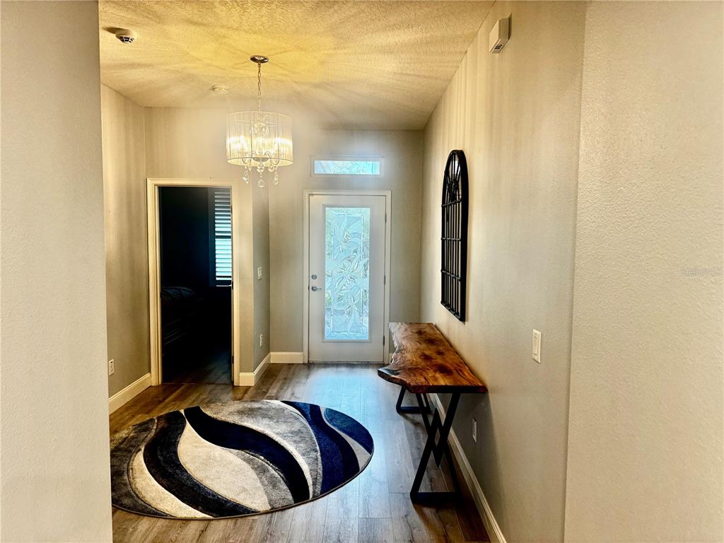 An entryway with wood-look flooring, a round rug, a live-edge console table, and a chandelier — 5088 ENDVIEW PASS, BROOKSVILLE, FL