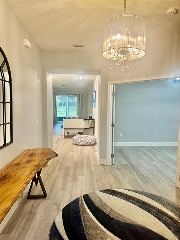 A foyer with light wood flooring, a live-edge console table, and a crystal chandelier — 5088 ENDVIEW PASS, BROOKSVILLE, FL