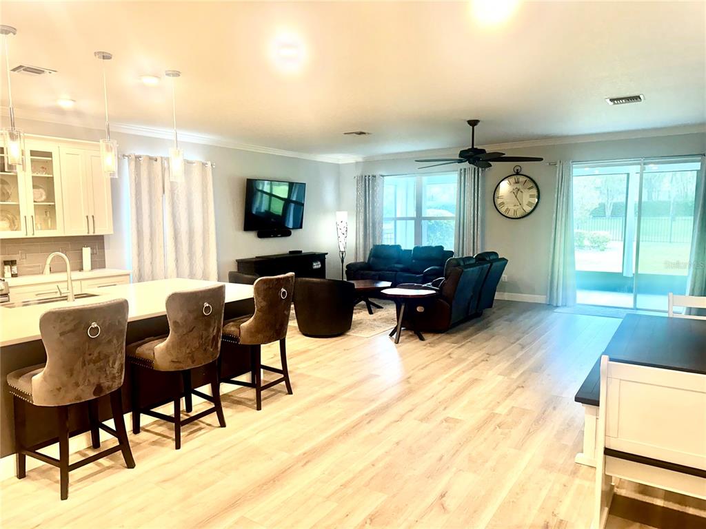 An open-concept kitchen and living area features a large island, bar seating, and hardwood flooring — 5088 ENDVIEW PASS, BROOKSVILLE, FL