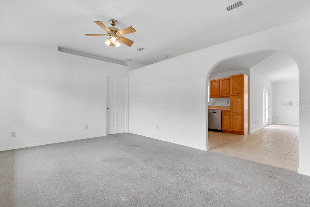 A living room with gray carpet leads through an arched opening into a tiled kitchen — 2225 MARYLAND AVENUE, TITUSVILLE, FL