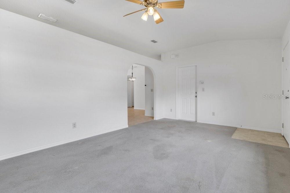 A living room with gray carpet, white walls, a ceiling fan, and an arched doorway — 2225 MARYLAND AVENUE, TITUSVILLE, FL