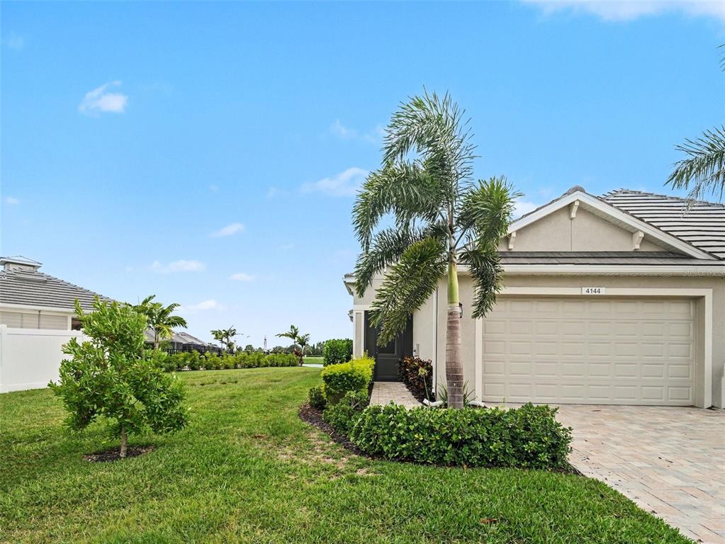 A single-story house exterior features a beige garage, a palm tree, and a grassy yard — 4144 GOLDEN CREEK TERRACE, PARRISH, FL