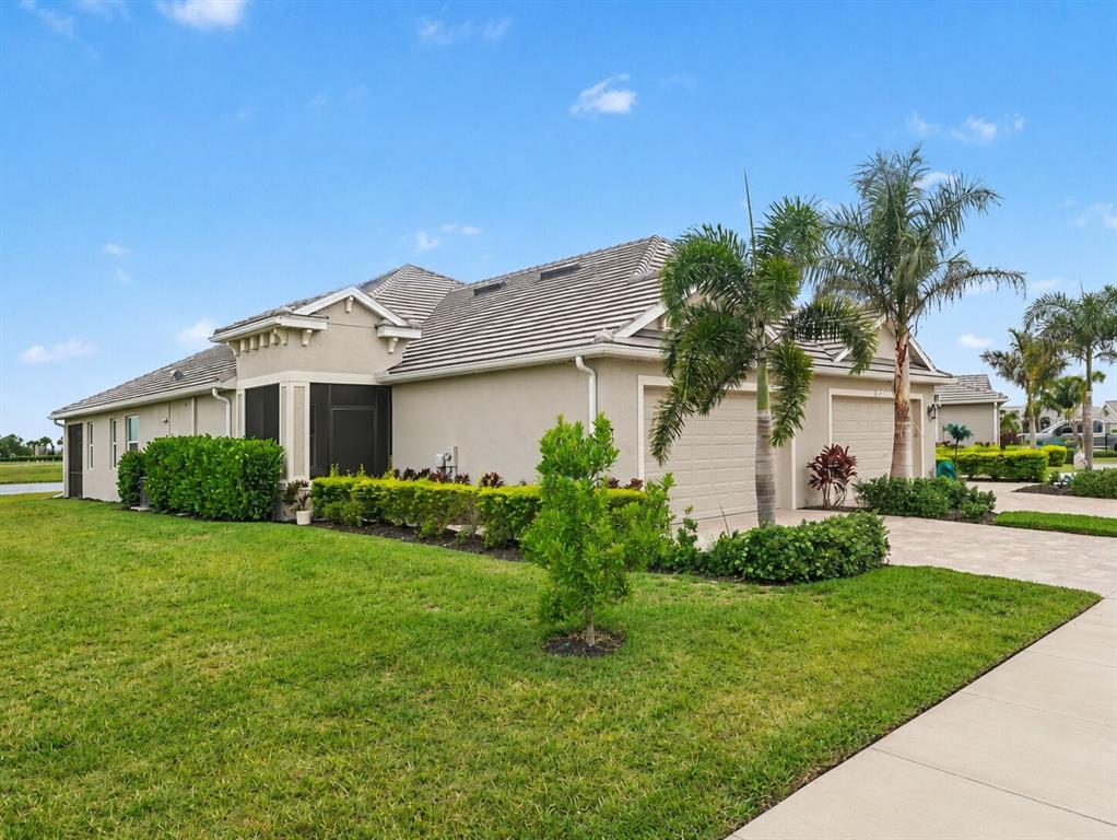A beige house with a tiled roof, two garage doors, and a manicured lawn — 4144 GOLDEN CREEK TERRACE, PARRISH, FL