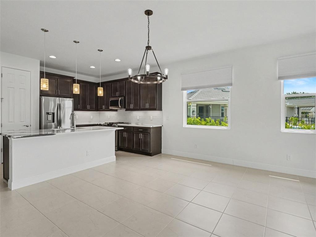 A kitchen with dark cabinets and a white island opens to a dining area — 4144 GOLDEN CREEK TERRACE, PARRISH, FL