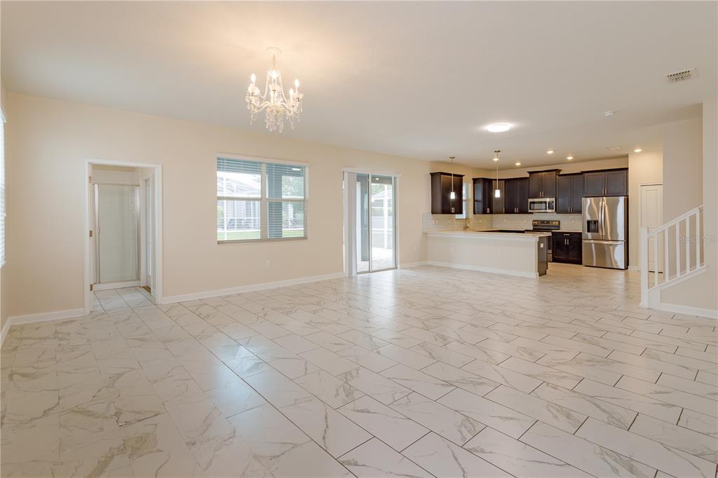 An open-concept living area features white marble-look tile flooring, a crystal chandelier, and a kitchen — 1673 MOON VALLEY DRIVE, DAVENPORT, FL