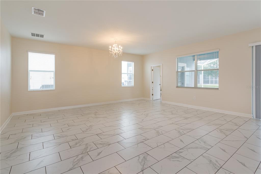 An empty room with light-colored walls, white marble-look tile flooring, and a crystal chandelier — 1673 MOON VALLEY DRIVE, DAVENPORT, FL
