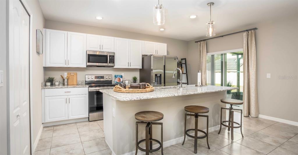 A kitchen features white cabinets, granite countertops, stainless steel appliances, and a central island — 8643 TEMPEST DRIVE, CITRUS SPRINGS, FL
