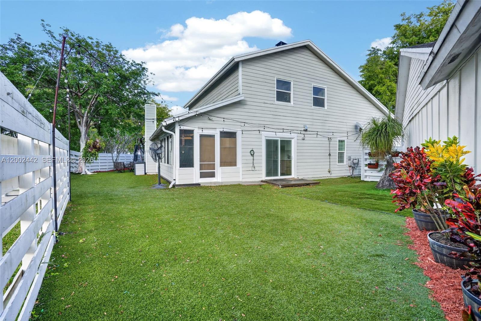The exterior of a two-story house features light gray siding, a screened porch, and a lawn — 14914 SW 142nd Pl, Miami FL 33186, MIAMI, FL