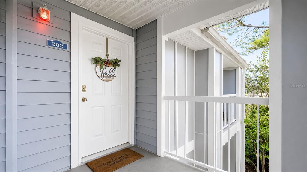 An exterior view of a white apartment door with a fall wreath and welcome mat — 2548 GRASSY POINT DRIVE UNIT 202, LAKE MARY, FL