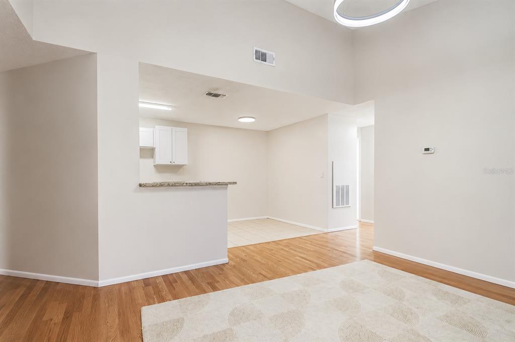 A living room with hardwood floors and a rug opens to a kitchen with tile — 2548 GRASSY POINT DRIVE UNIT 202, LAKE MARY, FL