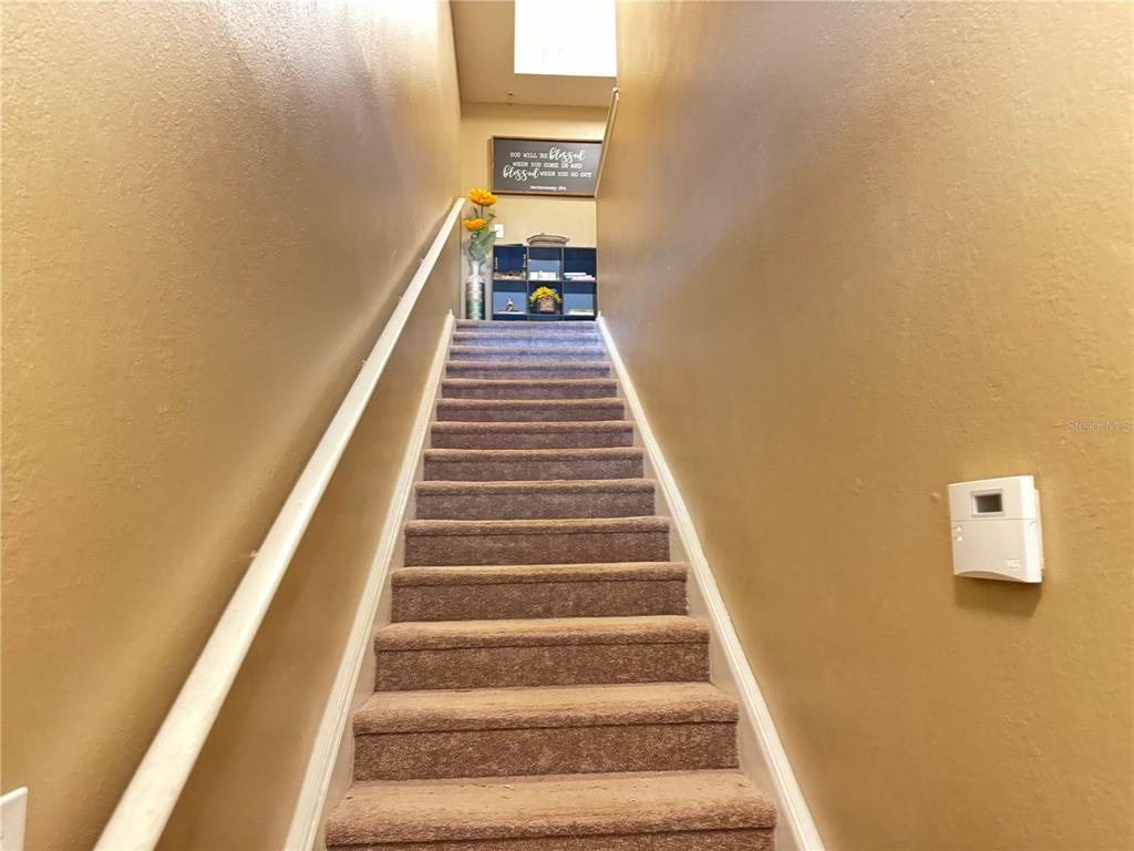 A carpeted staircase leads upward between two tan walls with a white handrail — 1101 VINTAGE VILLAGE LANE UNIT 108, OCOEE, FL