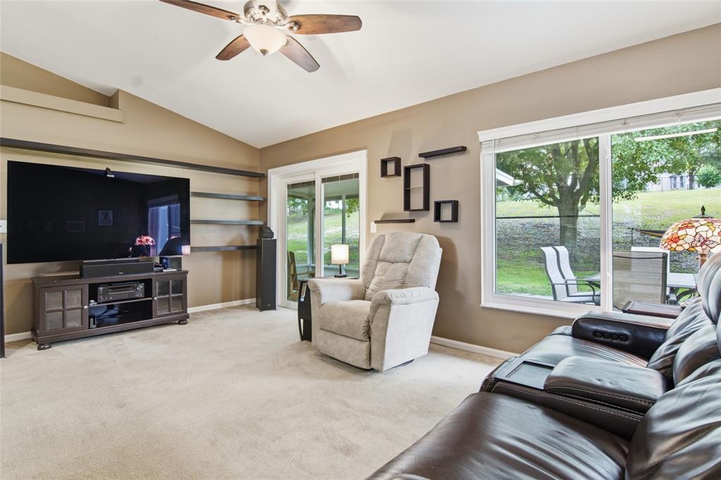 A living room features a large television, a recliner, a leather sofa, and sliding glass doors — 13326 PINYON DRIVE, CLERMONT, FL