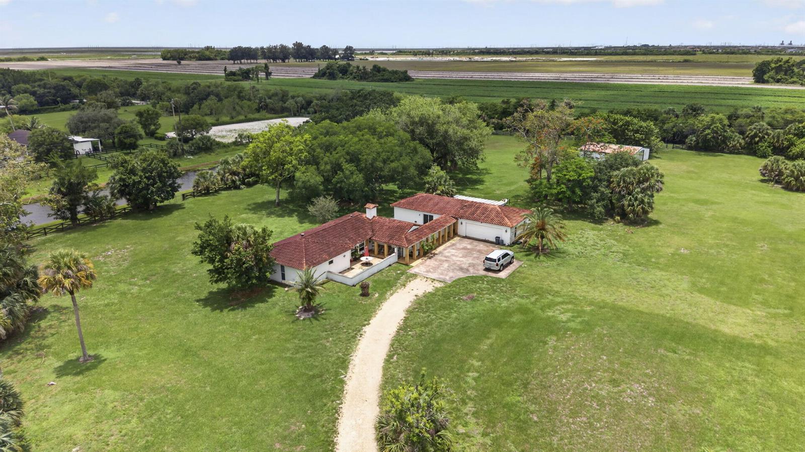 An aerial view shows a single-story house with a red tile roof and gravel driveway — 1029 Arabian Drive, Loxahatchee FL 33470, LOXAHATCHEE, FL