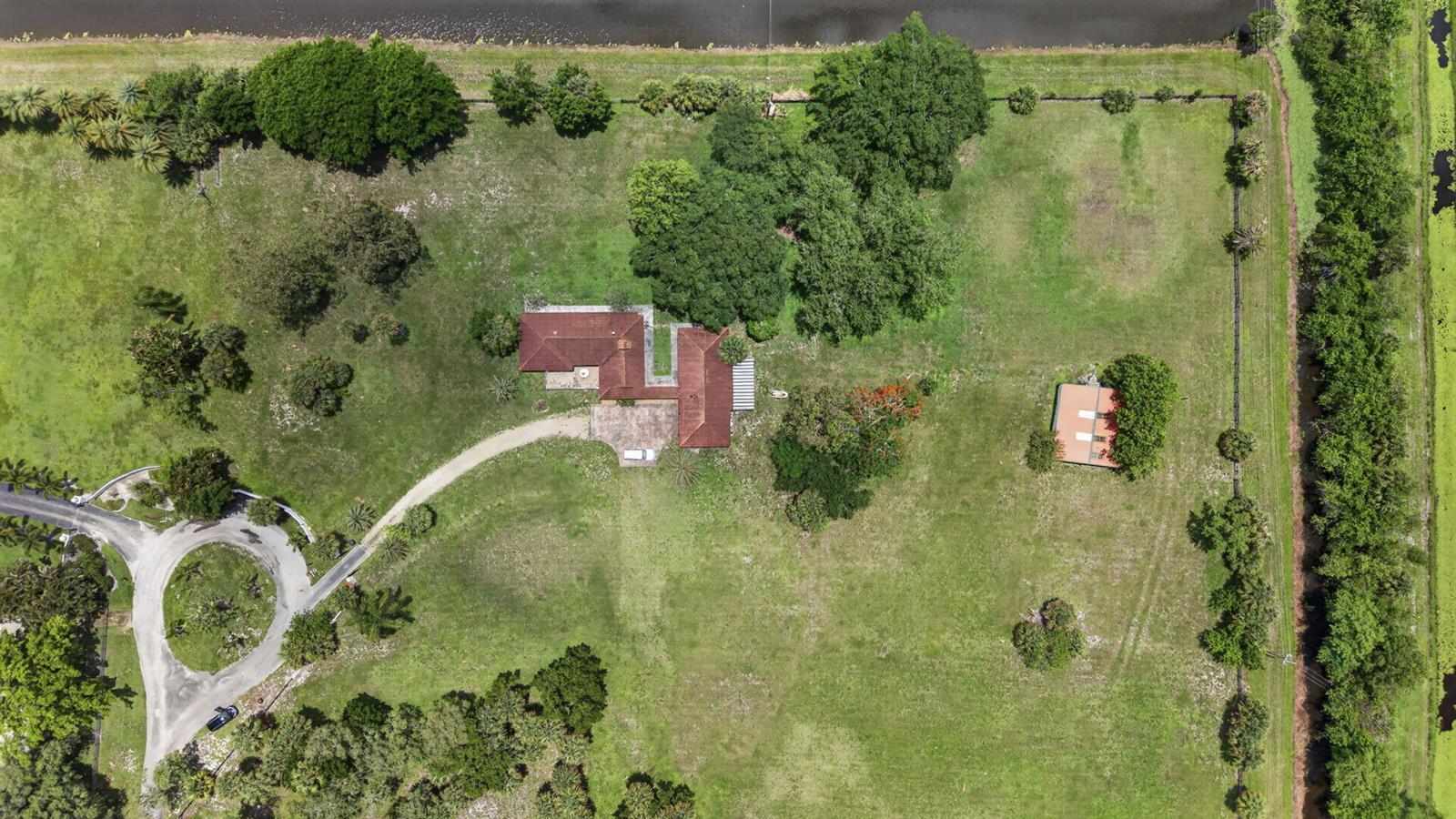 An aerial view shows a house with a red roof, a driveway, and a detached building — 1029 Arabian Drive, Loxahatchee FL 33470, LOXAHATCHEE, FL
