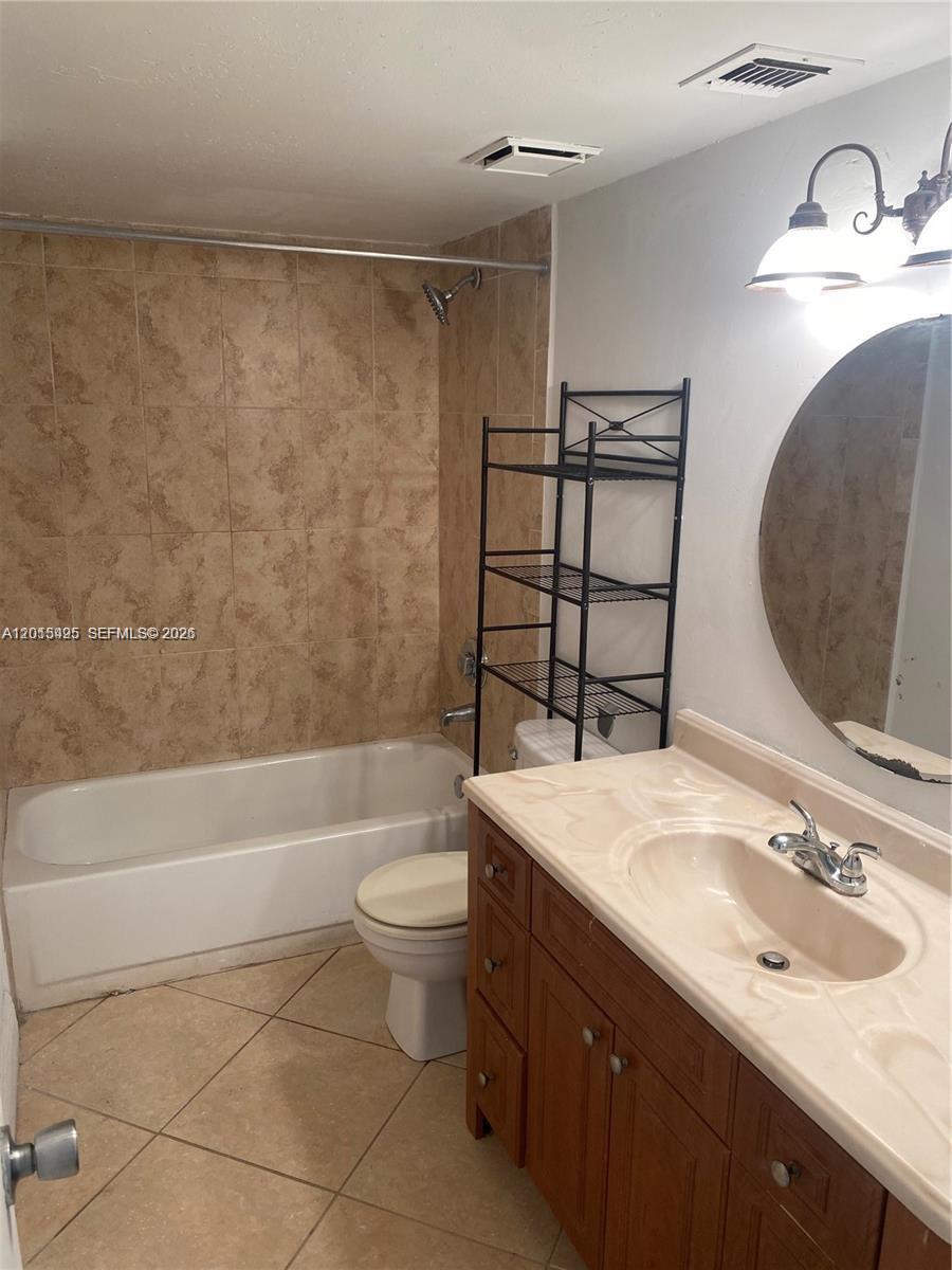 A bathroom features a vanity, toilet, and a tiled shower-tub combination — 18330 NW 68th Ave # G, Hialeah FL 33015, HIALEAH, FL