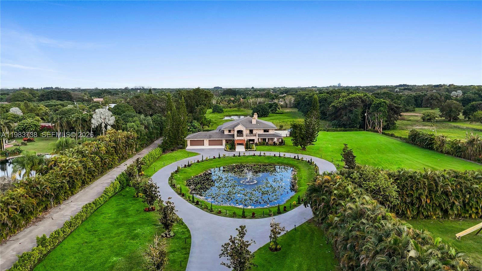 An aerial view shows a large stone house with a circular driveway and pond — 3320 SW 121st Ave, Davie FL 33330, DAVIE, FL