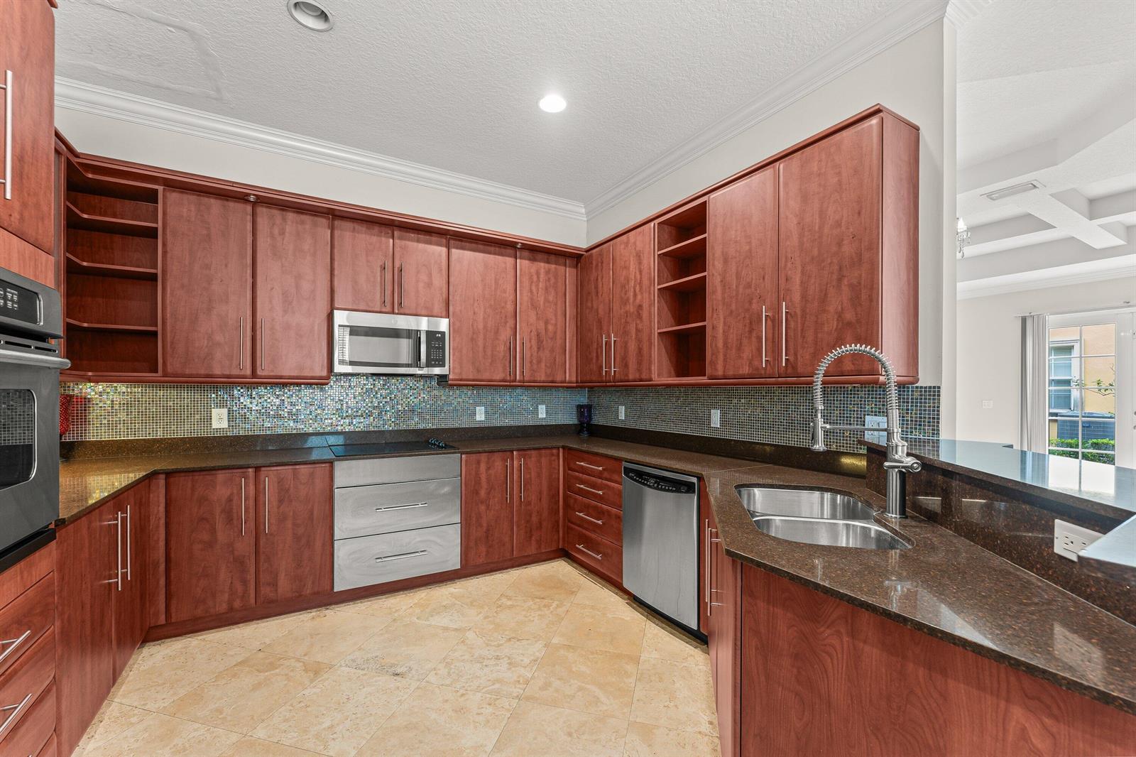 A kitchen features cherry wood cabinets, granite countertops, stainless steel appliances, and a mosaic backsplash — 210 NE 69th Circle, Boca Raton FL 33487, BOCA RATON, FL