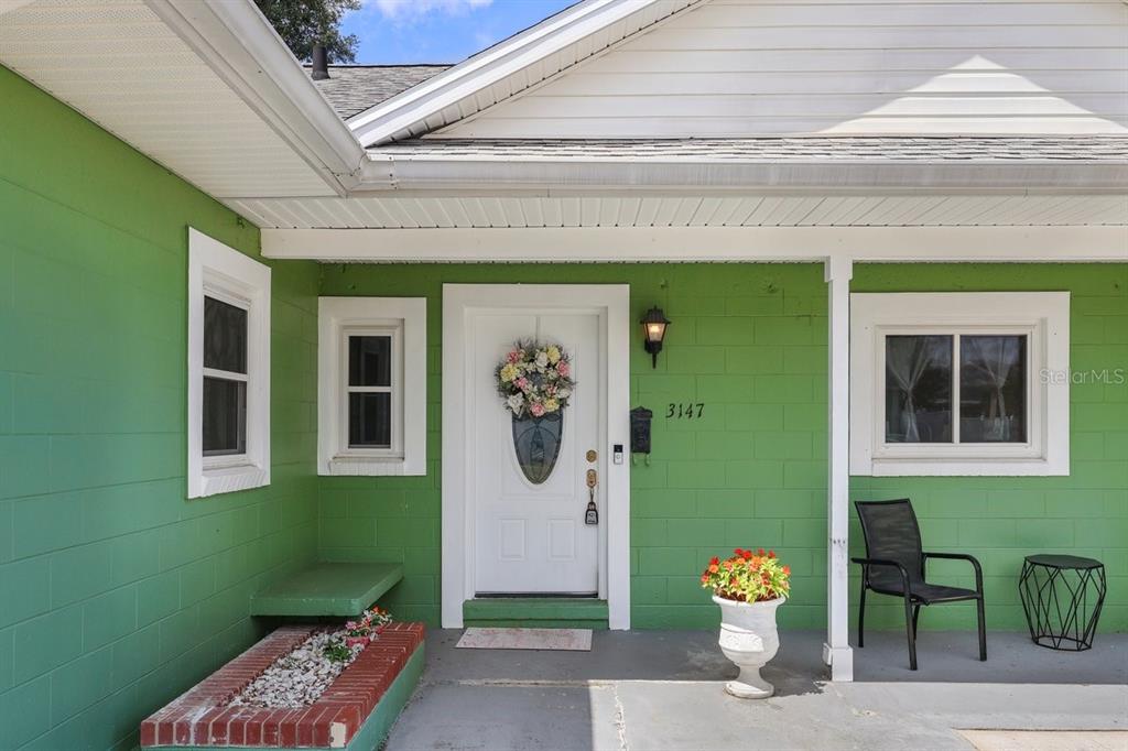 The exterior of a house features green concrete block walls, a white door, and a porch — 3147 ANDROS PLACE, ORLANDO, FL