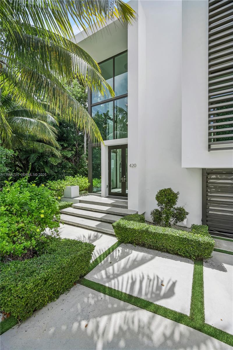 The exterior of a modern white house features a glass entryway and landscaped front yard — 420 N Hibiscus Dr, Miami Beach FL 33139, MIAMI BEACH, FL