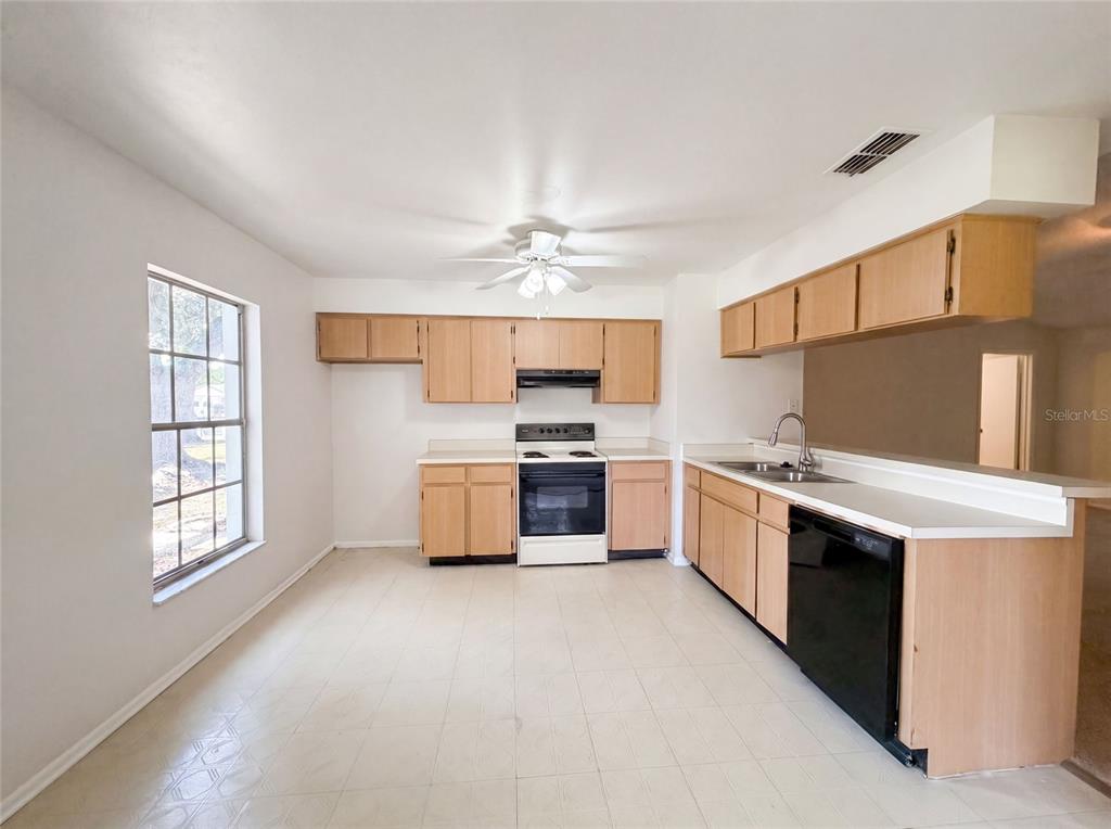 A kitchen with light wood cabinets, white countertops, a black dishwasher, and a white stove — 5720 KNEELAND LANE, TAMPA, FL