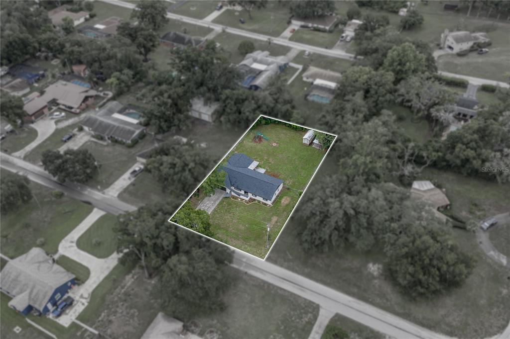 An aerial view shows a single-family house with a large backyard on a residential lot — 37320 MOORE DRIVE, DADE CITY, FL