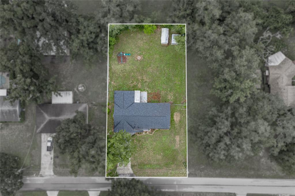 An aerial view shows a house with a dark roof situated on a large lot — 37320 MOORE DRIVE, DADE CITY, FL