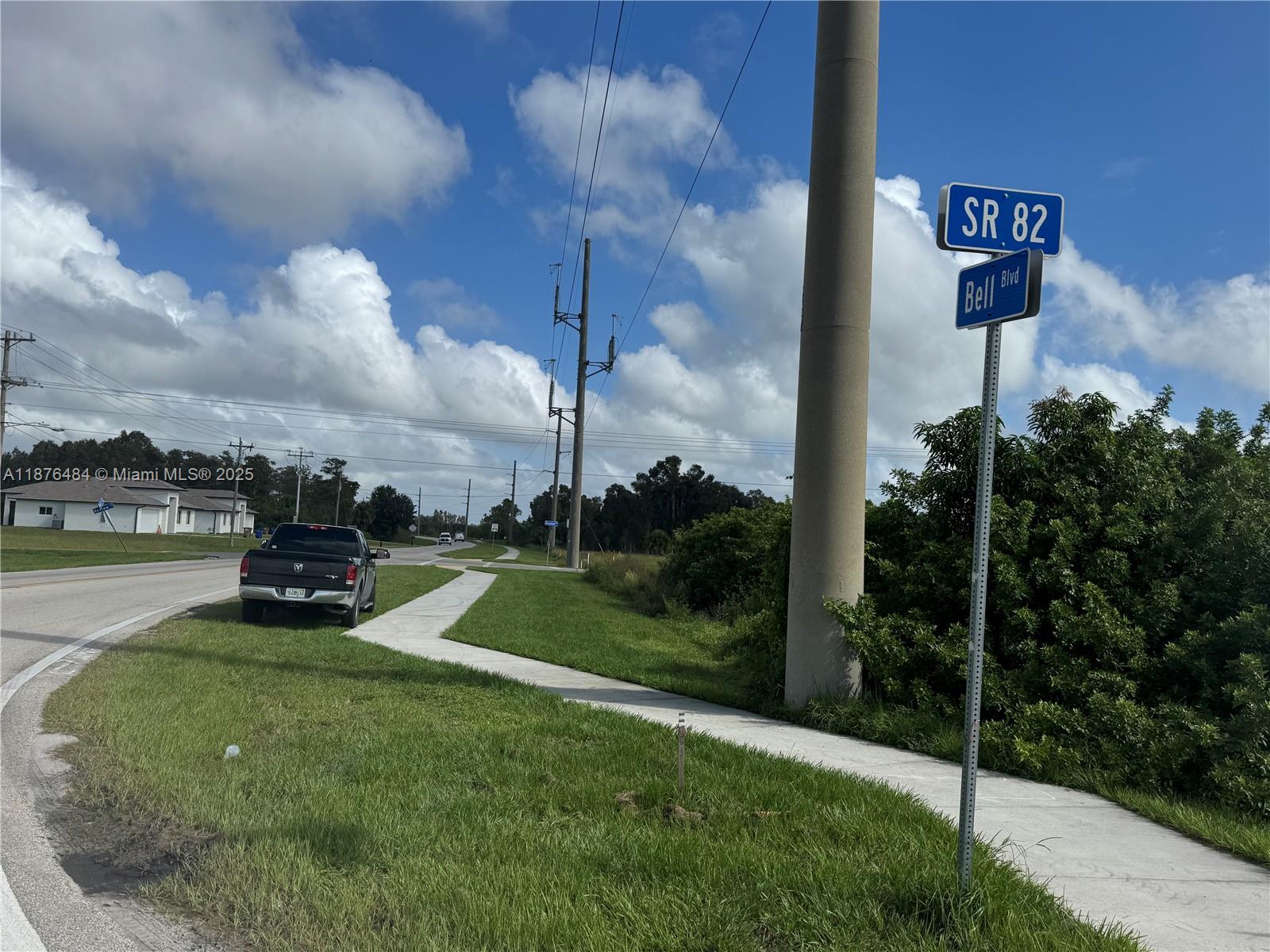 A street sign for SR 82 and Bell Blvd stands beside a sidewalk and road — 861 BARCIA, Lehigh Acres FL 33974, LEHIGH ACRES, FL