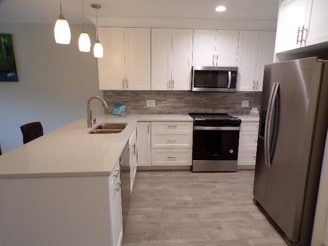 A modern kitchen features white cabinets, stainless steel appliances, a stone backsplash, and a peninsula — 2248 NE 37th Street, Lighthouse Point FL 33064, LIGHTHOUSE POINT, FL