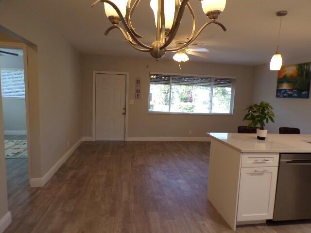 A kitchen island with a white cabinet faces a dining area with wood-look flooring — 2248 NE 37th Street, Lighthouse Point FL 33064, LIGHTHOUSE POINT, FL