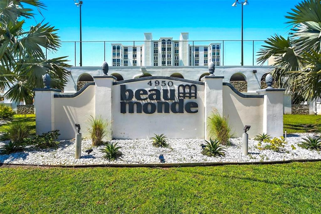 A white monument sign for Beau Monde stands in front of a multi-story residential building — 4950 GULF BOULEVARD UNIT 501, ST PETE BEACH, FL
