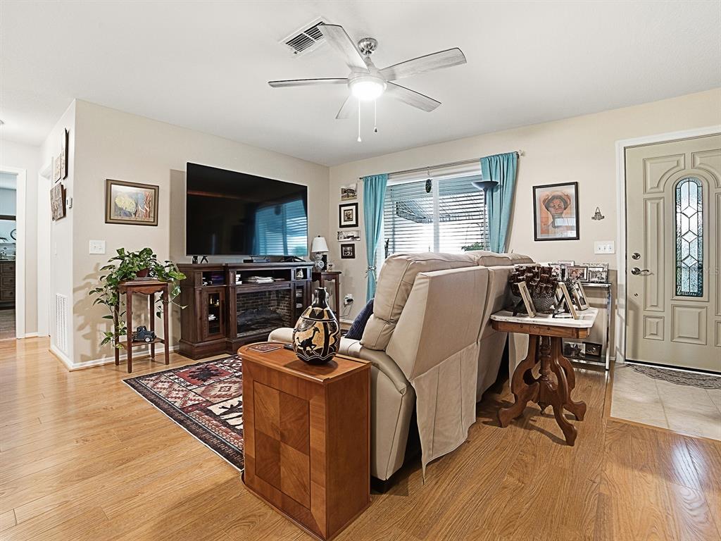 A living room features a television, a recliner, a ceiling fan, and hardwood flooring — 1507 GARDENA COURT, THE VILLAGES, FL