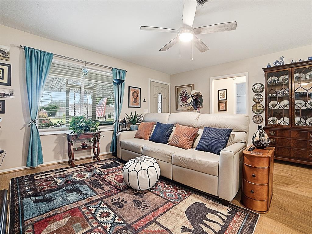 A living room features a light-colored sofa, a patterned area rug, and a wooden hutch — 1507 GARDENA COURT, THE VILLAGES, FL