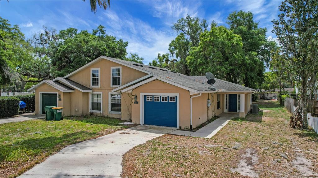 A tan, single-story house with a blue garage door and a concrete driveway — 305 W FOUNTAIN STREET, FRUITLAND PARK, FL
