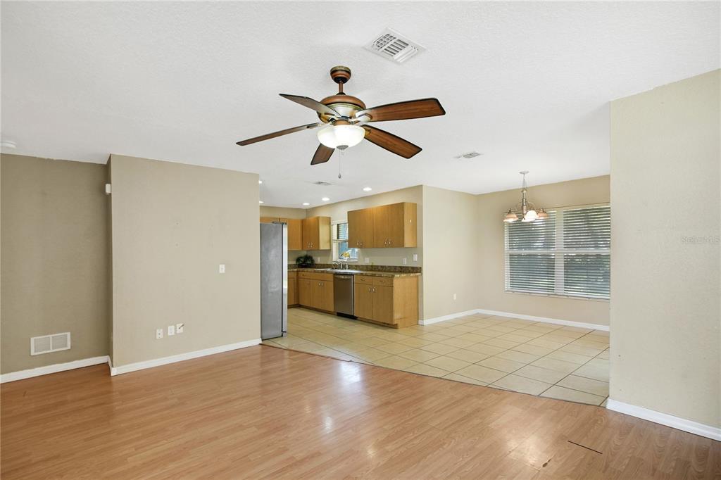 An open-concept room features a wood-floored living area, a tiled kitchen, and a dining space — 305 W FOUNTAIN STREET, FRUITLAND PARK, FL