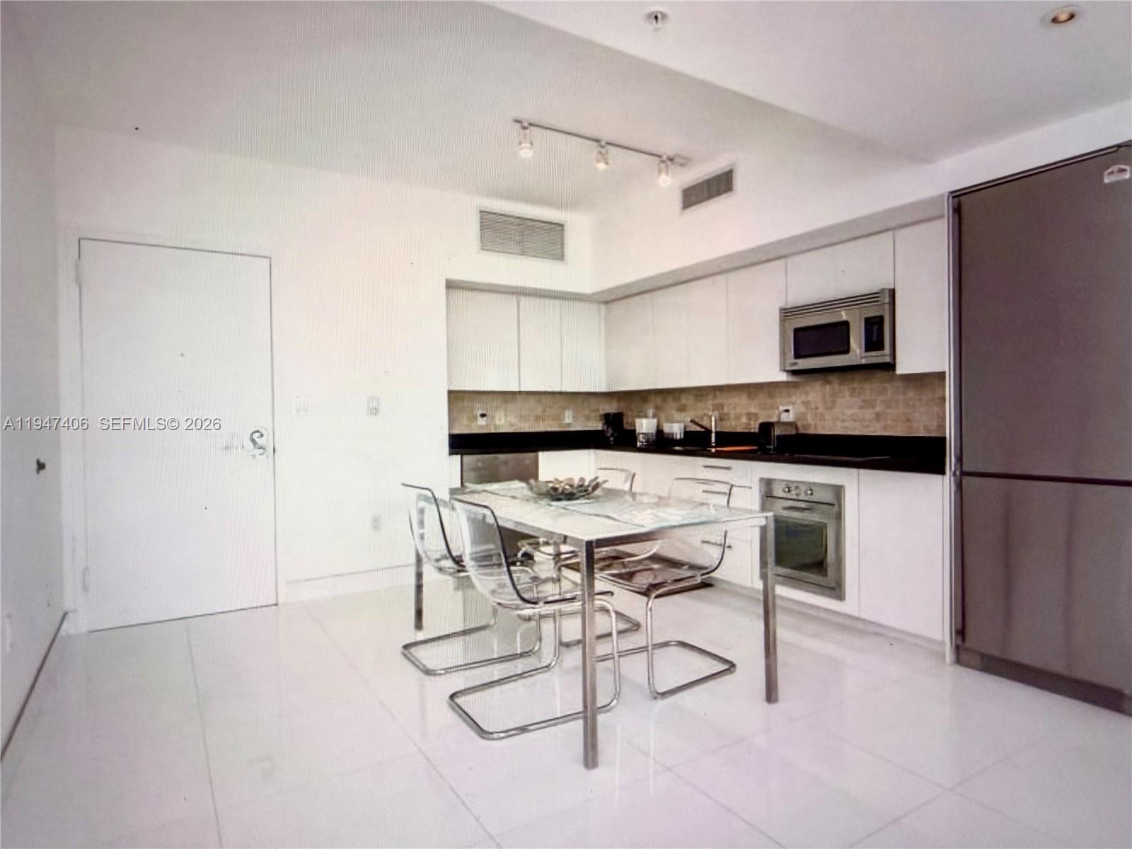 A kitchen with white cabinets, stainless steel appliances, and a glass dining table — 92 SW 3rd St # 4309, Miami FL 33130, MIAMI, FL