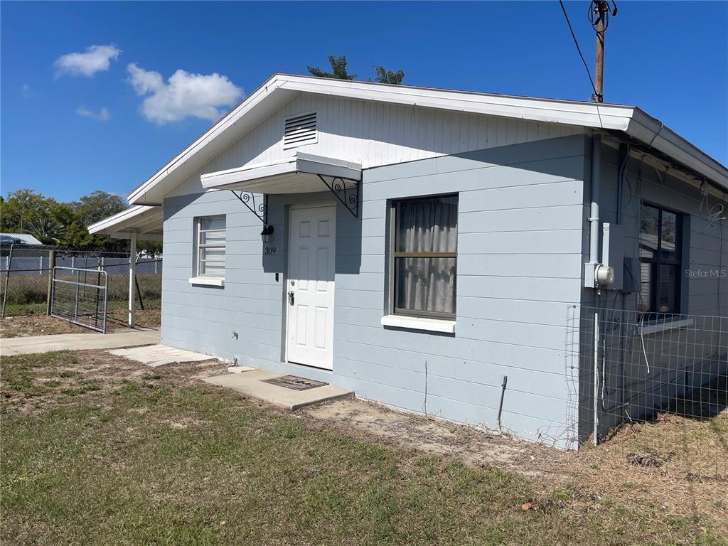 A single-story house with light blue siding, a white door, and a small metal awning — 309 CENTER STREET, AUBURNDALE, FL