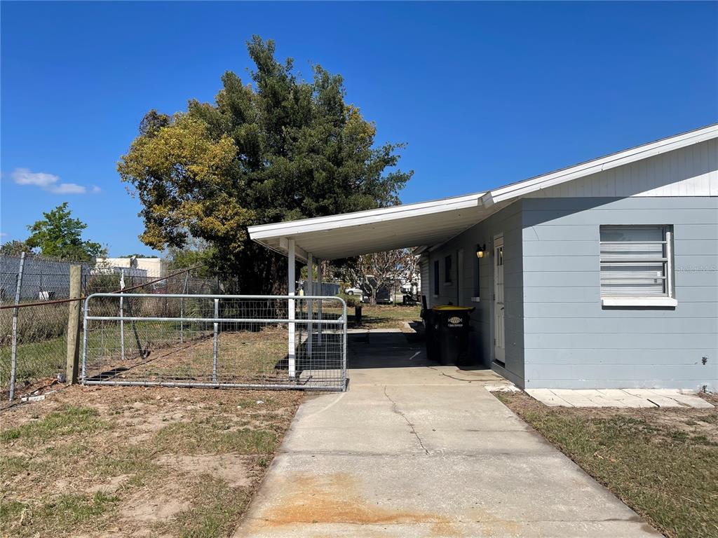 A concrete driveway leads to a covered carport attached to the side of a house — 309 CENTER STREET, AUBURNDALE, FL