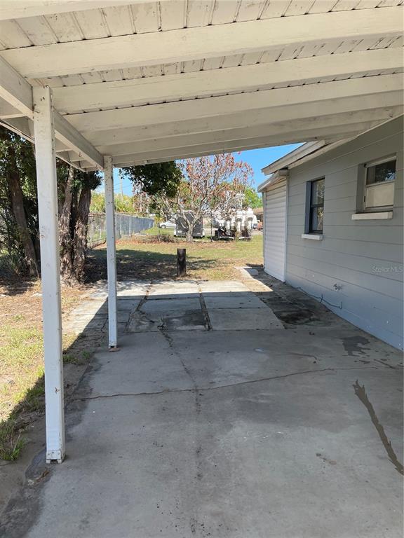 A concrete carport attached to the side of a gray house with a grassy yard — 309 CENTER STREET, AUBURNDALE, FL
