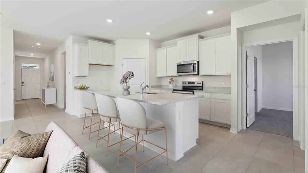A modern kitchen features white cabinetry, granite countertops, a center island, and barstool seating — 8171 IVES PLACE, WILDWOOD, FL